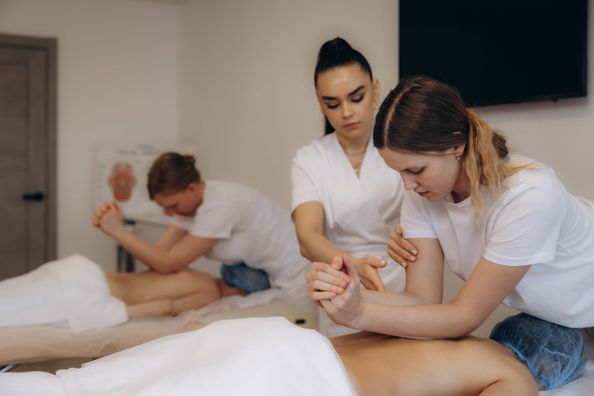Therapists practising supervised massage technique in a training setting